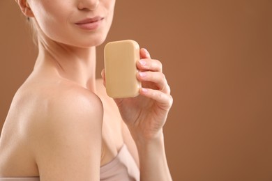 Photo of Woman with soap bar on brown background, closeup. Space for text