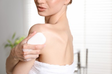 Photo of Woman with soap bar in bathroom, closeup
