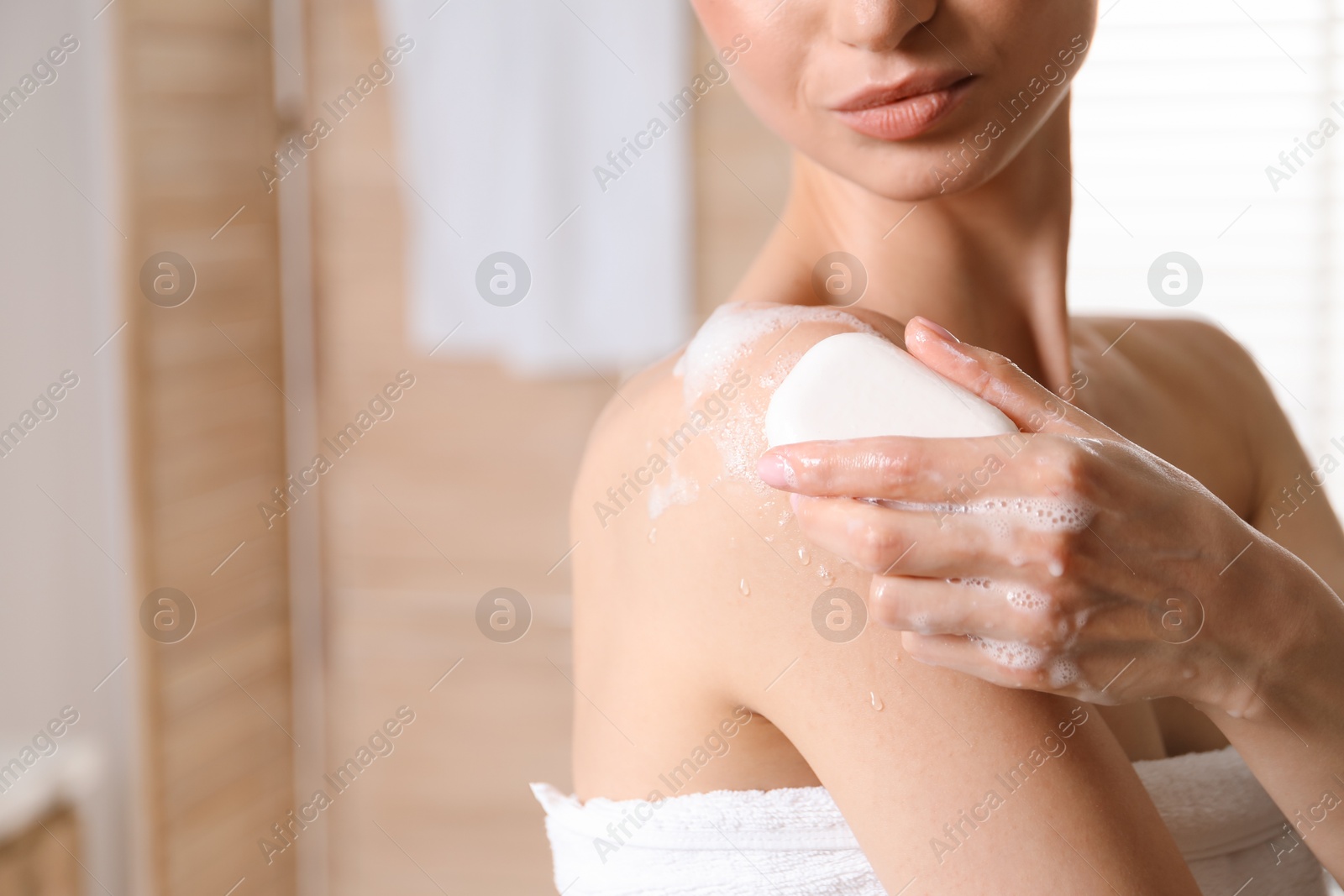 Woman washing body with soap bar indoors, closeup. Space for text Photo of Woman washing body with soap bar indoors, closeup. Space for text