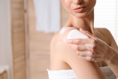 Photo of Woman washing body with soap bar indoors, closeup. Space for text