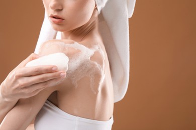 Photo of Woman washing body with soap bar on brown background, closeup. Space for text