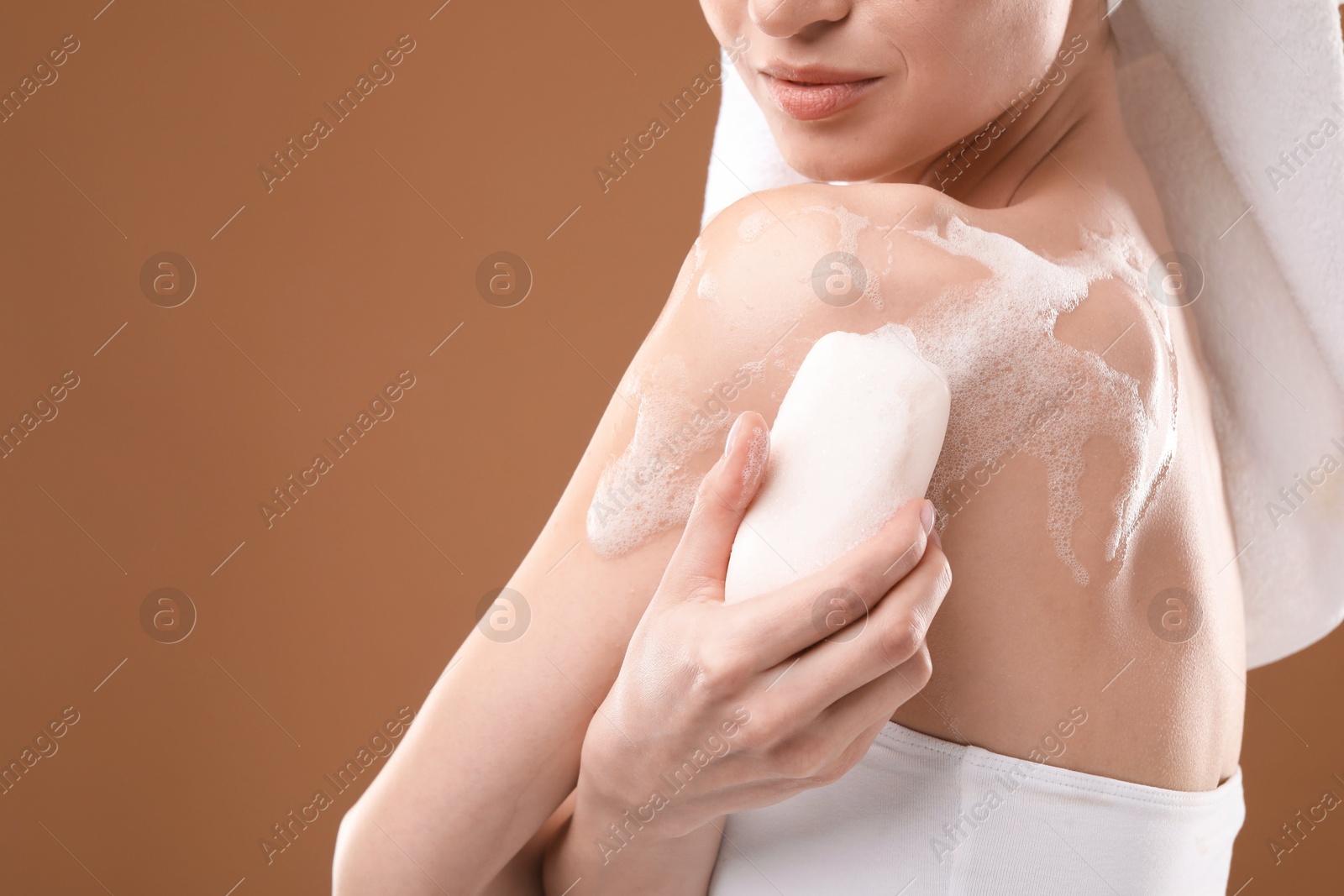 Woman washing body with soap bar on brown background, closeup. Space for text Photo of Woman washing body with soap bar on brown background, closeup. Space for text