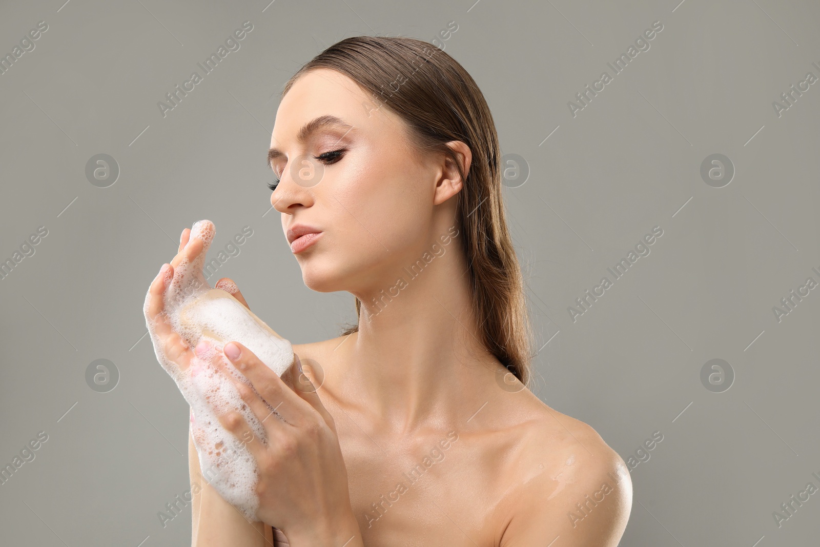 Beautiful woman washing hands with soap bar on grey background, closeup Photo of Beautiful woman washing hands with soap bar on grey background, closeup