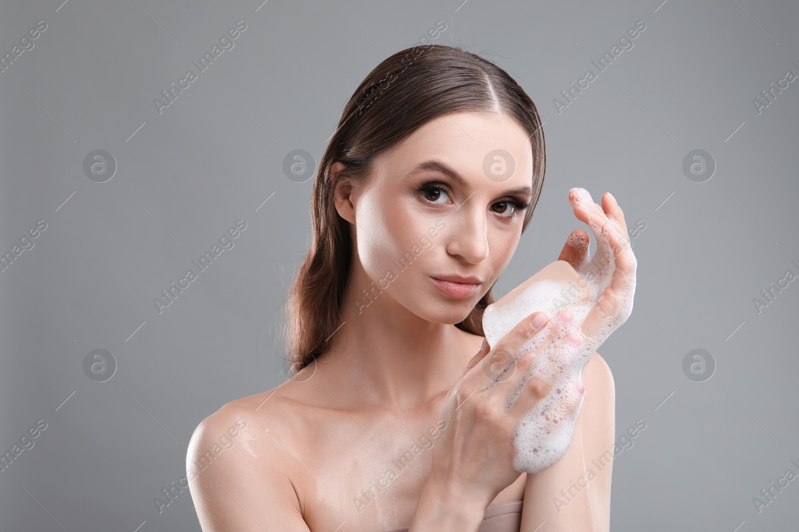 Beautiful woman washing hands with soap bar on grey background, closeup Photo of Beautiful woman washing hands with soap bar on grey background, closeup