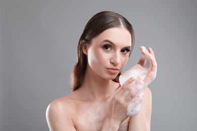 Photo of Beautiful woman washing hands with soap bar on grey background, closeup
