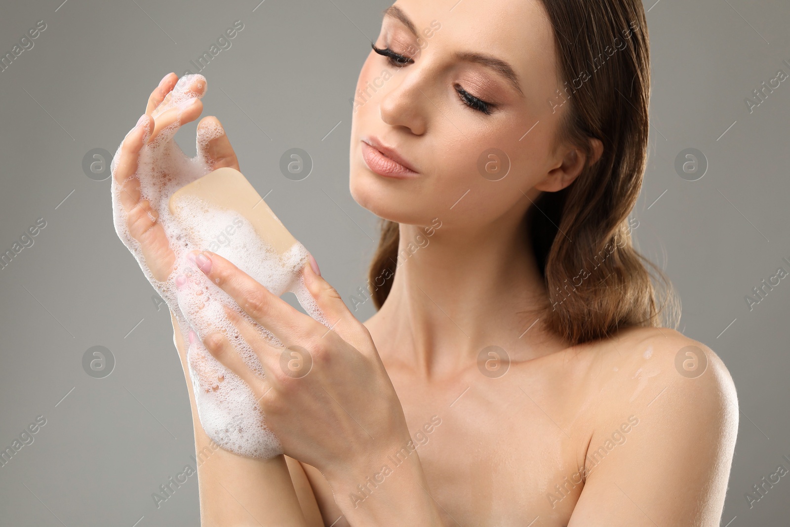 Beautiful woman washing hands with soap bar on grey background, closeup Photo of Beautiful woman washing hands with soap bar on grey background, closeup