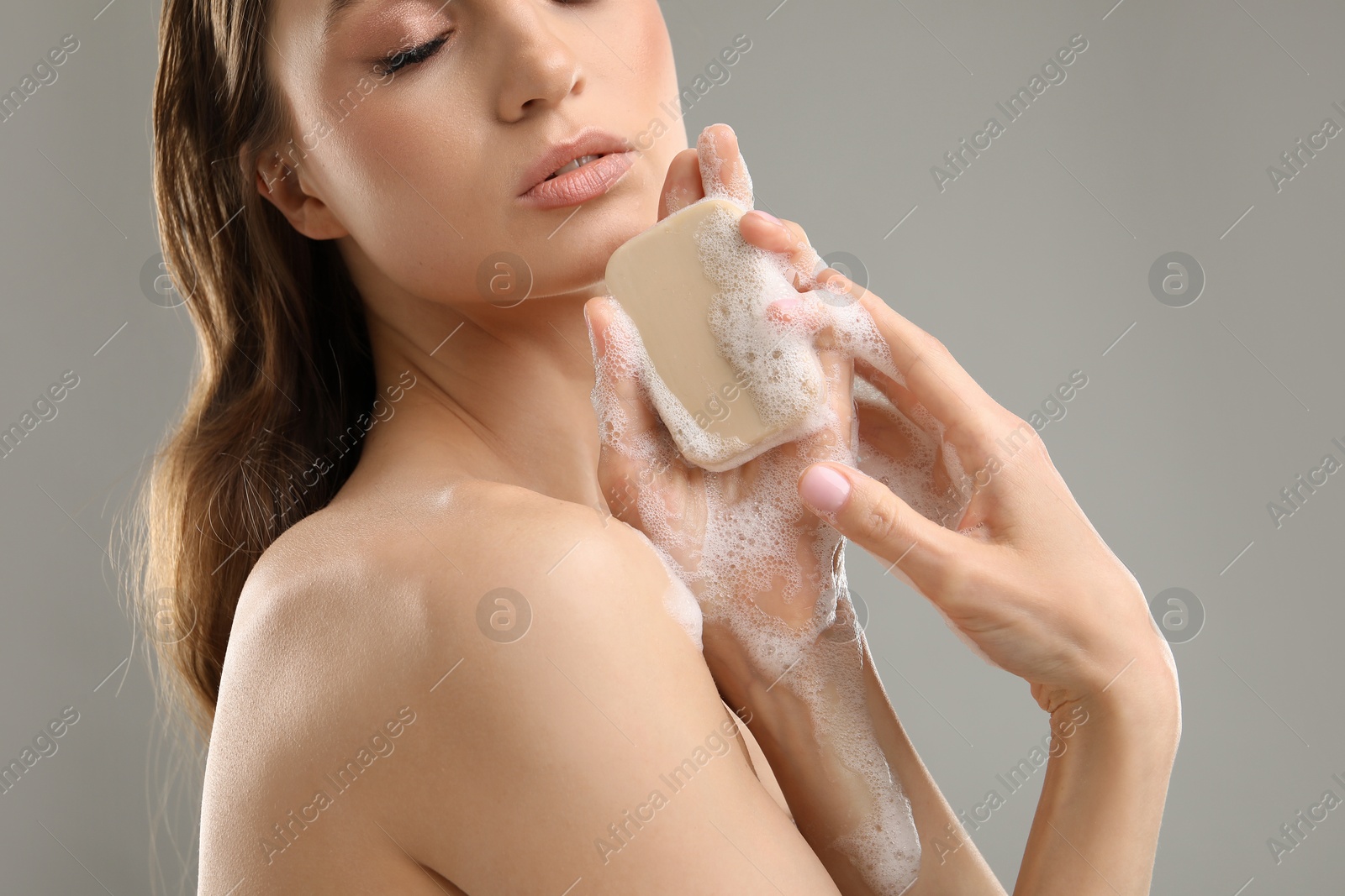 Beautiful woman with soap bar on grey background, closeup Photo of Beautiful woman with soap bar on grey background, closeup