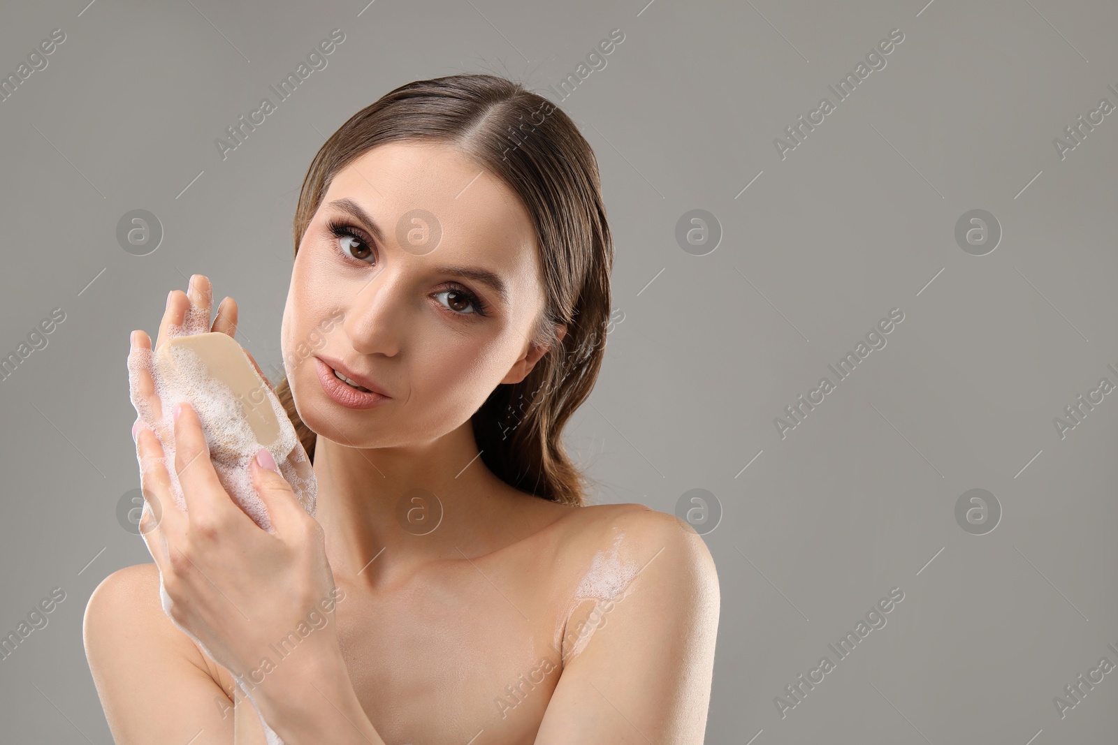 Beautiful woman washing hands with soap bar on grey background. Space for text Photo of Beautiful woman washing hands with soap bar on grey background. Space for text