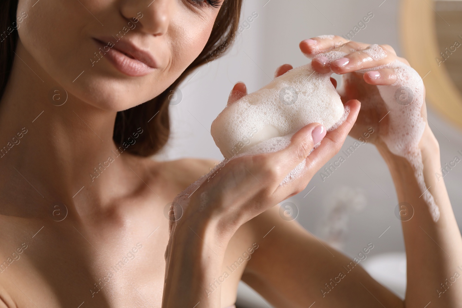 Woman with foaming soap bar indoors, closeup Photo of Woman with foaming soap bar indoors, closeup