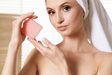 Photo of Beautiful woman with soap bar indoors, closeup
