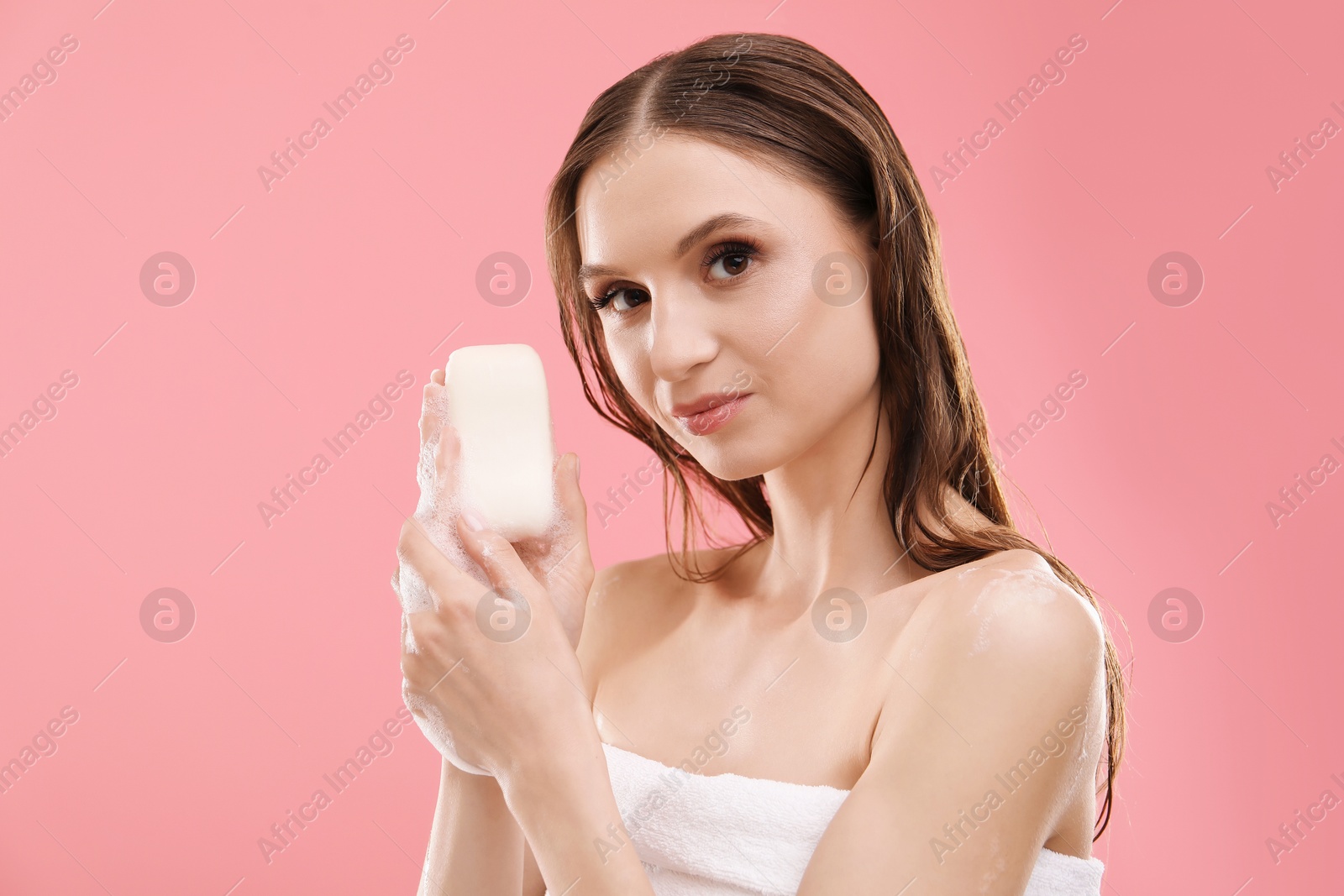 Woman with foaming soap bar on pink background Photo of Woman with foaming soap bar on pink background