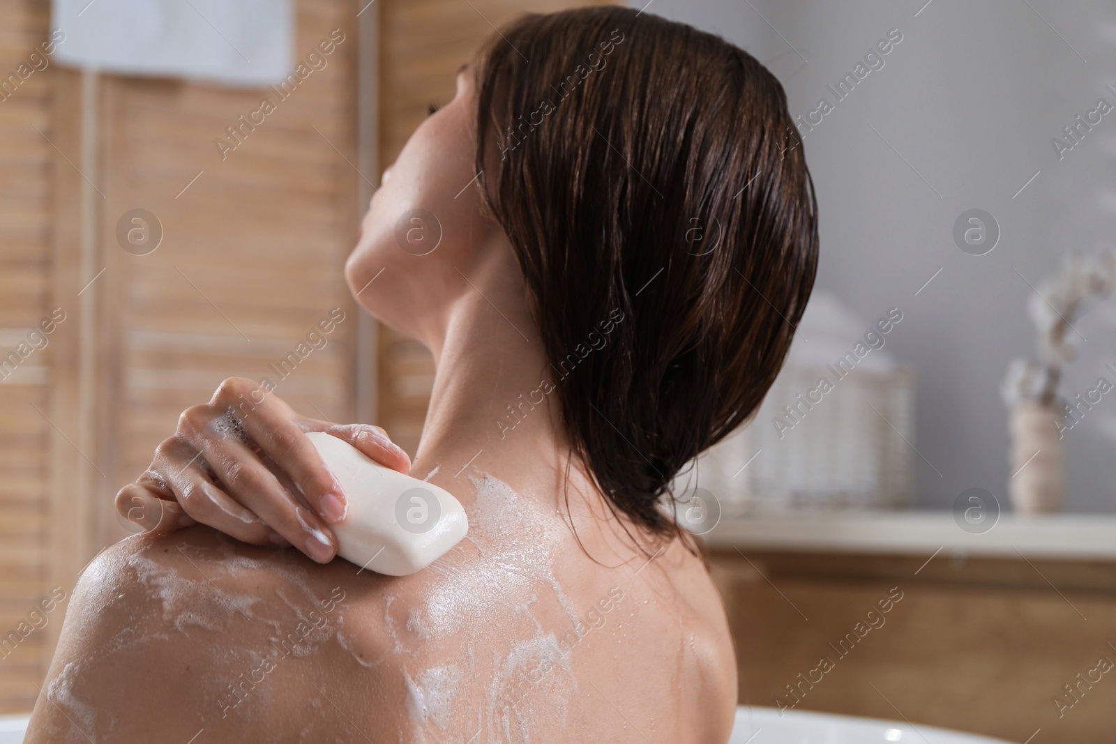 Woman washing body with soap bar in bathroom, closeup Photo of Woman washing body with soap bar in bathroom, closeup
