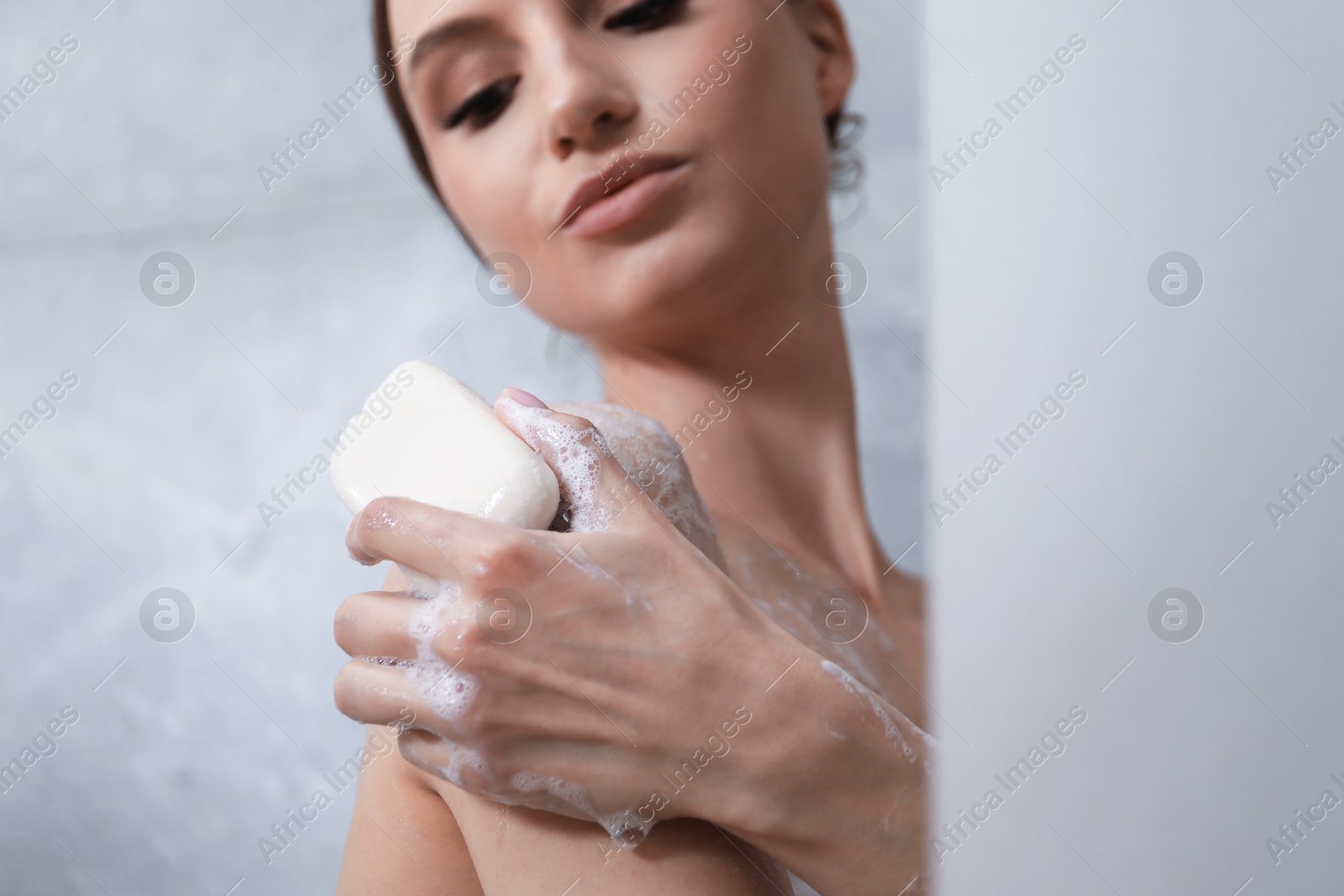Woman washing body with soap bar in bathroom, closeup Photo of Woman washing body with soap bar in bathroom, closeup
