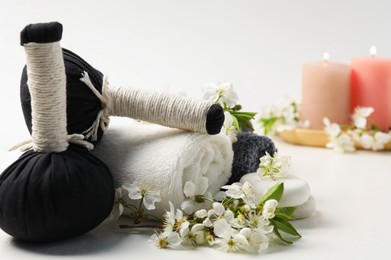 Photo of Spa composition with herbal bags, beautiful flowers and burning candles on white background, selective focus