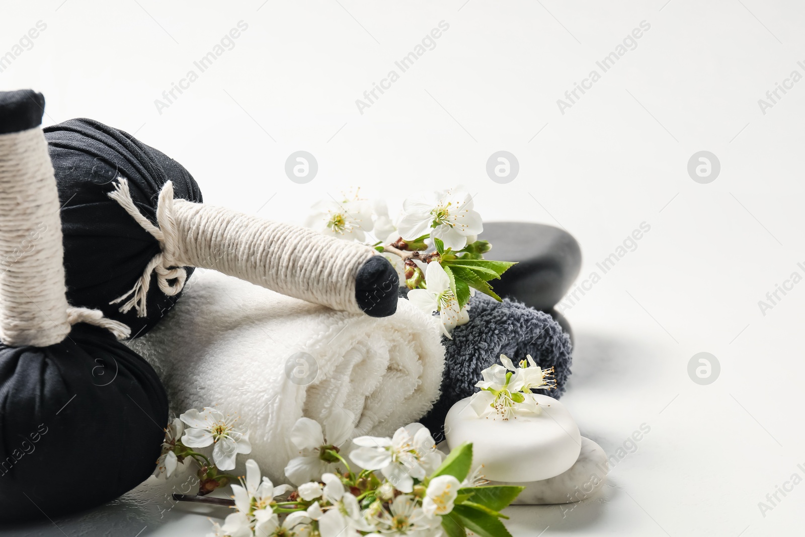 Spa composition with pebble stones, beautiful flowers and herbal bags on white background, closeup Photo of Spa composition with pebble stones, beautiful flowers and herbal bags on white background, closeup