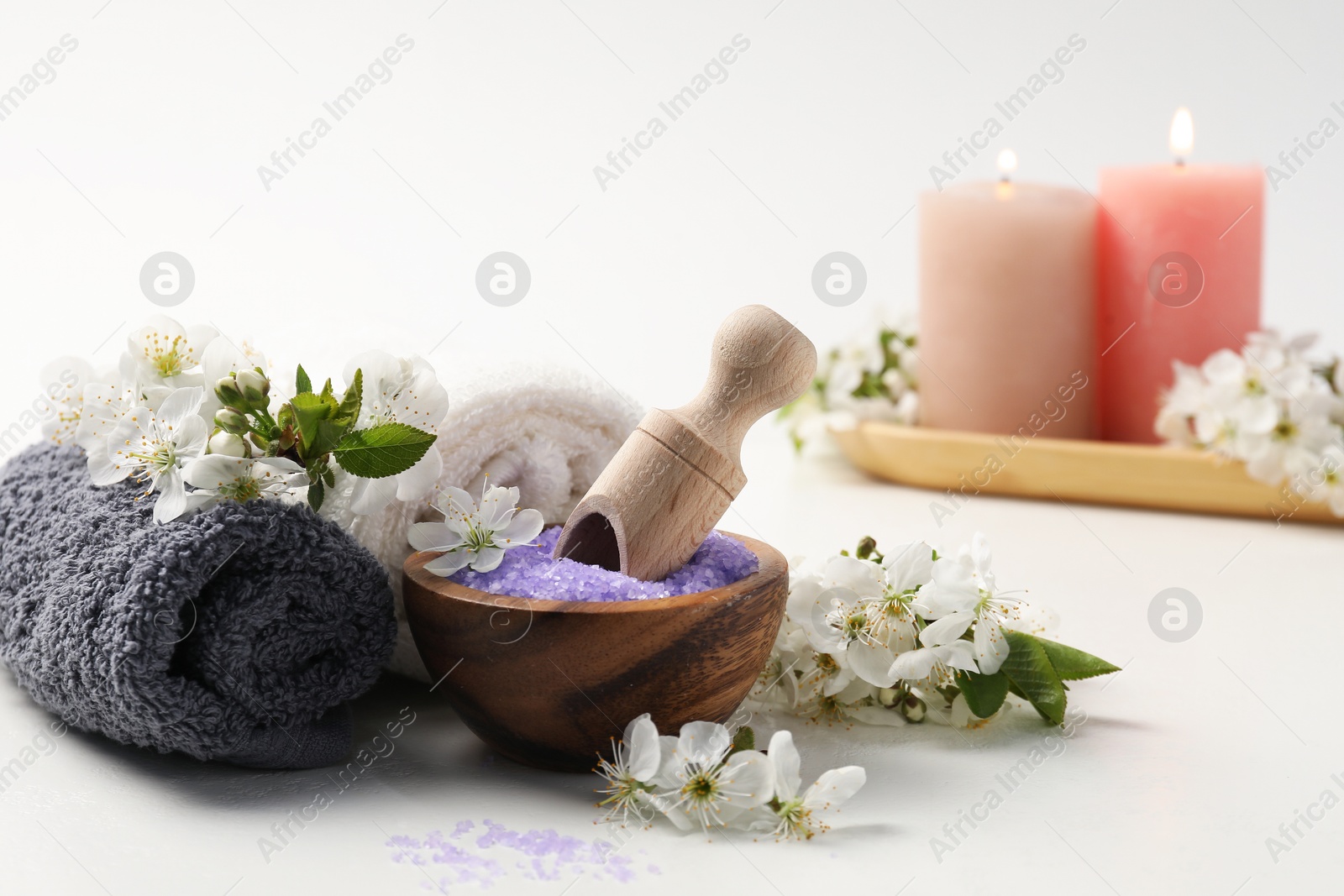 Spa composition with sea salt, beautiful flowers and burning candles on white background, selective focus Photo of Spa composition with sea salt, beautiful flowers and burning candles on white background, selective focus