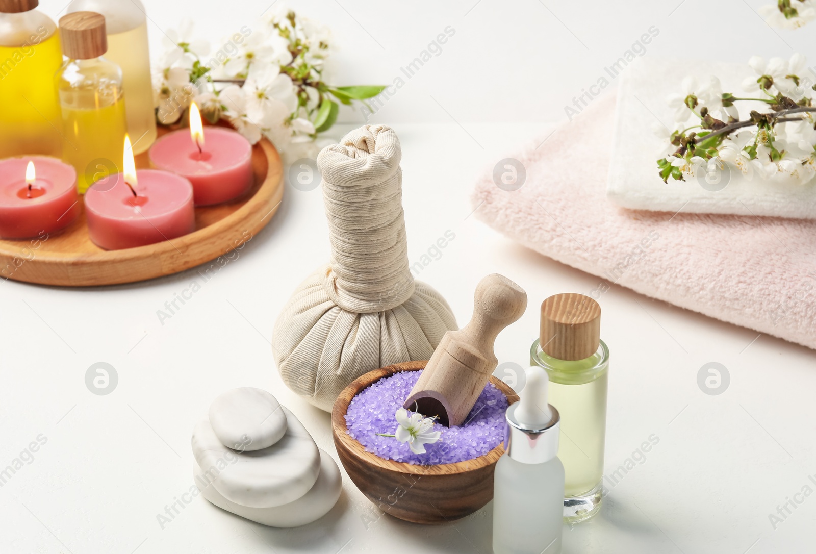 Composition with spa products, beautiful flowers and burning candles on white table, closeup Photo of Composition with spa products, beautiful flowers and burning candles on white table, closeup
