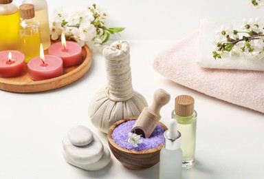 Photo of Composition with spa products, beautiful flowers and burning candles on white table, closeup