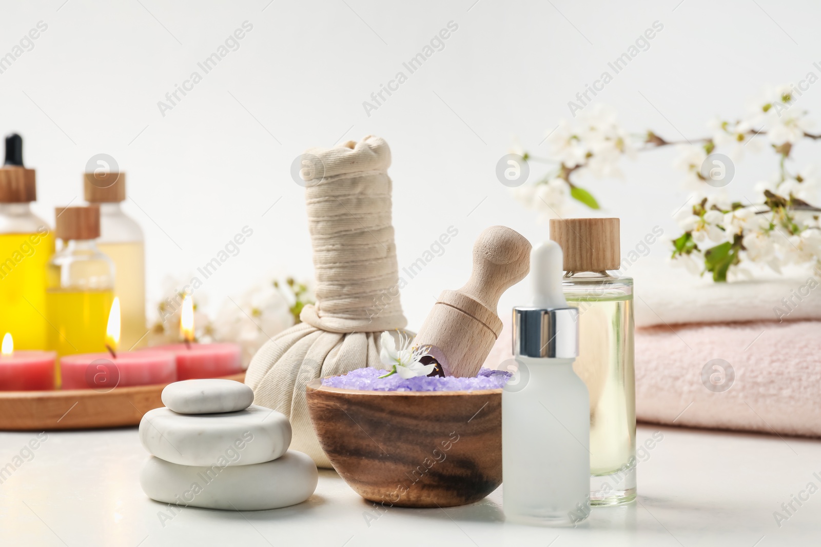 Composition with spa products, beautiful flowers and burning candles on white table, closeup Photo of Composition with spa products, beautiful flowers and burning candles on white table, closeup