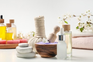 Photo of Composition with spa products, beautiful flowers and burning candles on white table, closeup