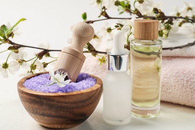 Photo of Composition with spa products and beautiful flowers on white textured table, closeup