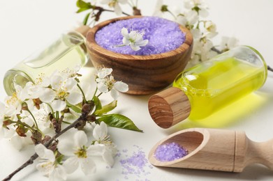 Photo of Spa products and twigs with beautiful flowers on white table, closeup