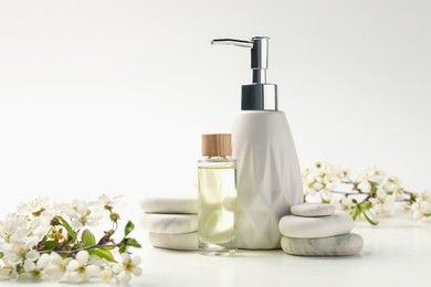Photo of Spa products, pebble stones and twigs with beautiful flowers on white table, closeup