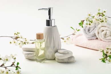 Photo of Spa products, pebble stones and twigs with beautiful flowers on white table, closeup