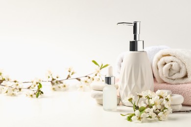 Photo of Spa products, pebble stones and twigs with beautiful flowers on white table, closeup