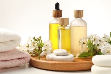 Photo of Spa products, pebble stones and twigs with beautiful flowers on white table, closeup