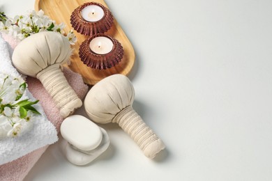 Photo of Spa products, burning candles, pebble stones and twigs with beautiful flowers on white background, flat lay. Space for text