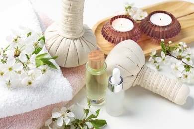 Photo of Spa products and twigs with beautiful flowers on white table, closeup
