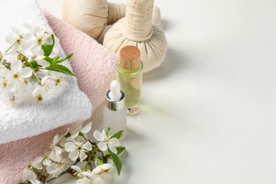 Photo of Spa products and twigs with beautiful flowers on white table, closeup. Space for text