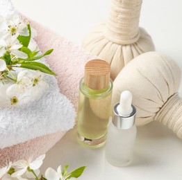 Photo of Spa products and twigs with beautiful flowers on white table, closeup