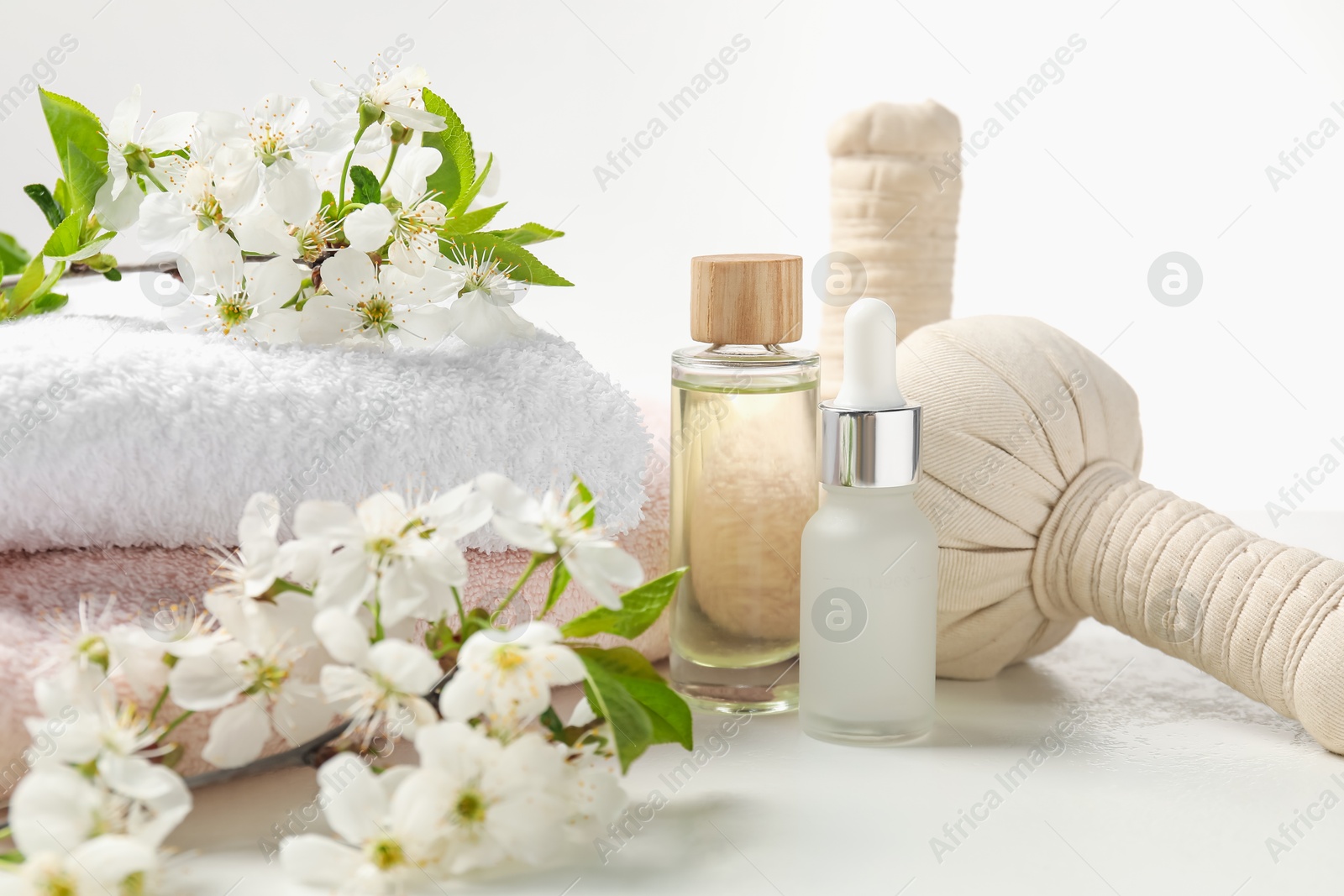 Spa products and twigs with beautiful flowers on white table, closeup Photo of Spa products and twigs with beautiful flowers on white table, closeup