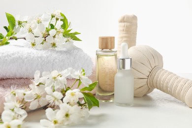 Photo of Spa products and twigs with beautiful flowers on white table, closeup