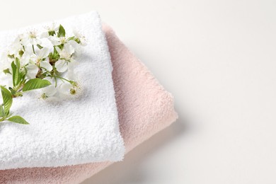 Photo of Towels and twigs with beautiful flowers on white table, closeup. Space for text