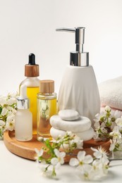 Photo of Spa products, pebble stones and twigs with beautiful flowers on white table, closeup