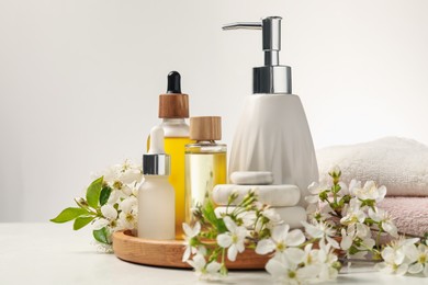 Photo of Spa products, pebble stones and twigs with beautiful flowers on white table, closeup