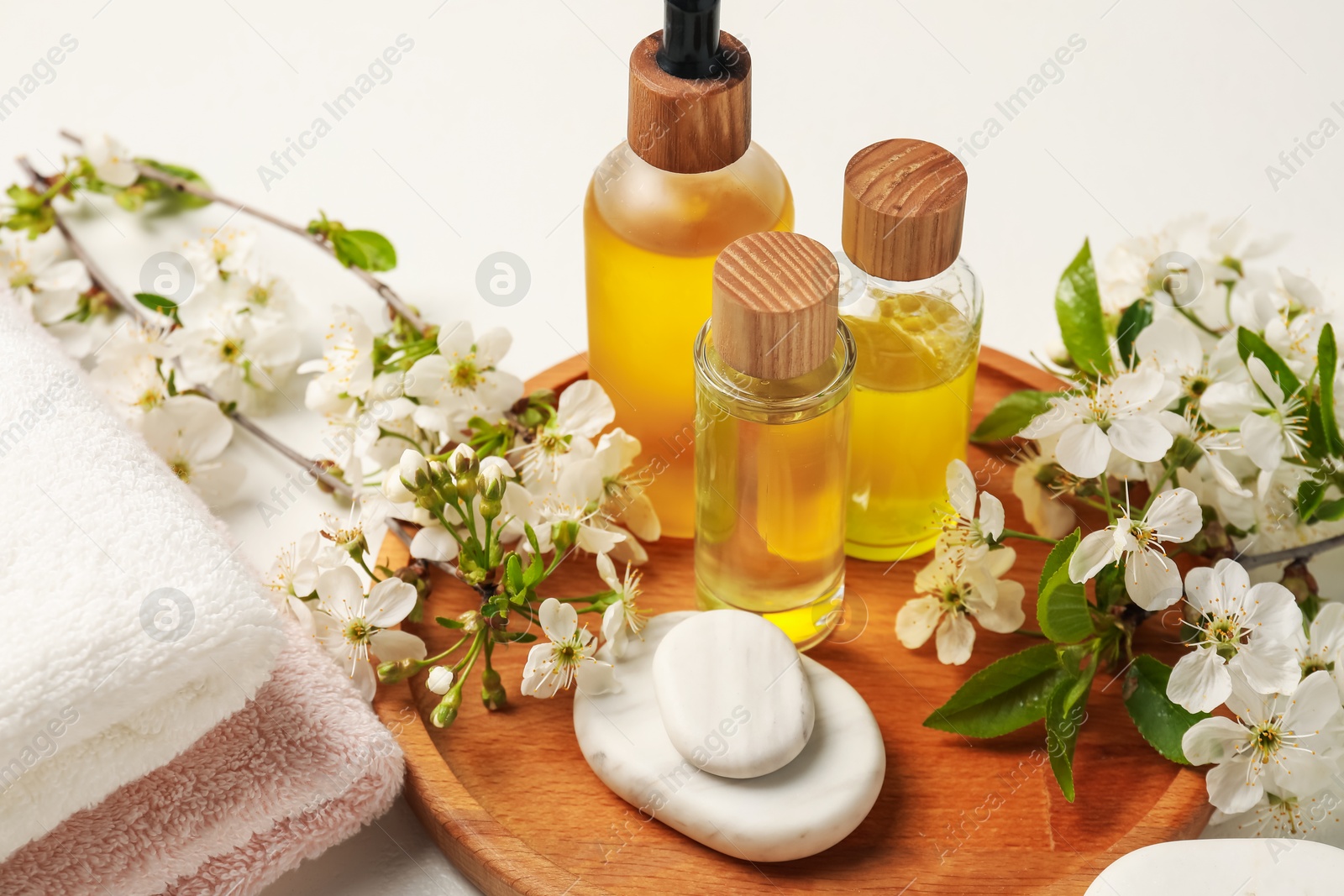 Spa products, pebble stones and twigs with beautiful flowers on white table, closeup Photo of Spa products, pebble stones and twigs with beautiful flowers on white table, closeup