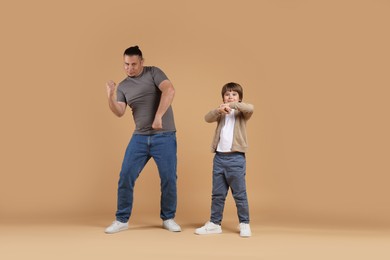 Photo of Father and his son dancing together on beige background