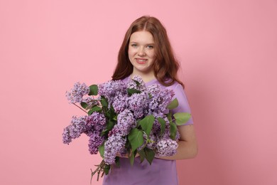 Photo of Portrait of smiling teenage girl with lilac flowers on pink background
