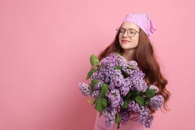 Photo of Beautiful teenage girl with bouquet of lilac flowers on pink background. Space for text