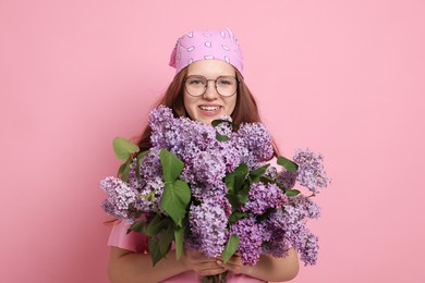 Photo of Portrait of smiling teenage girl with lilac flowers on pink background
