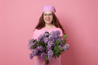 Photo of Portrait of smiling teenage girl with lilac flowers on pink background