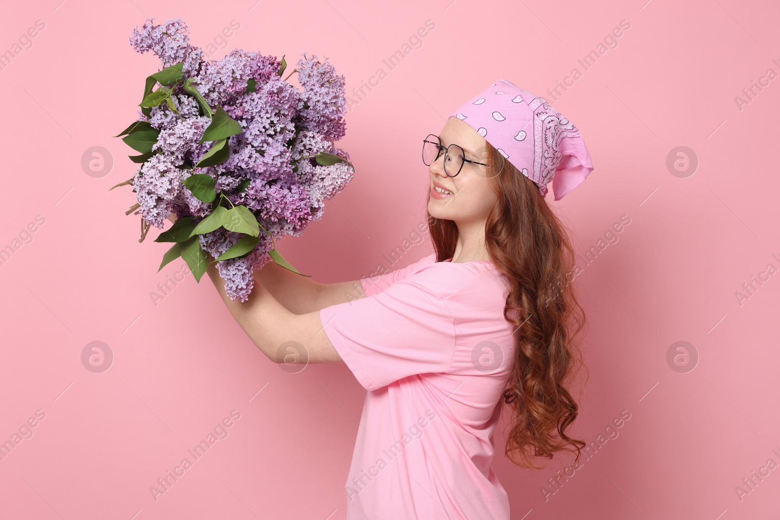 Smiling teenage girl with bouquet of lilac flowers on pink background Photo of Smiling teenage girl with bouquet of lilac flowers on pink background