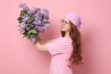 Photo of Smiling teenage girl with bouquet of lilac flowers on pink background