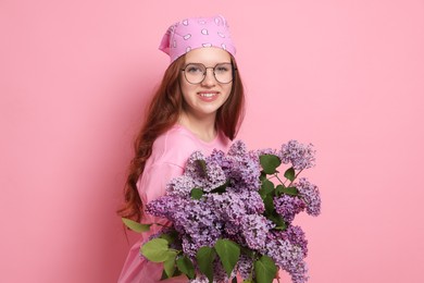 Photo of Portrait of smiling teenage girl with lilac flowers on pink background