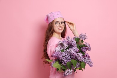 Photo of Portrait of smiling teenage girl with lilac flowers on pink background