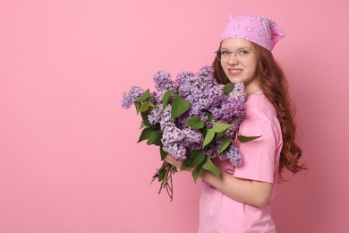 Photo of Smiling teenage girl with bouquet of lilac flowers on pink background. Space for text